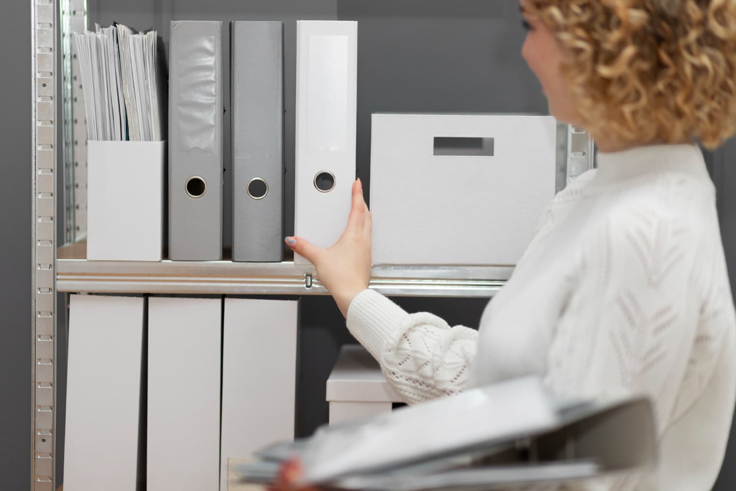 A neatly organized stationery cupboard with labeled boxes and supplies.