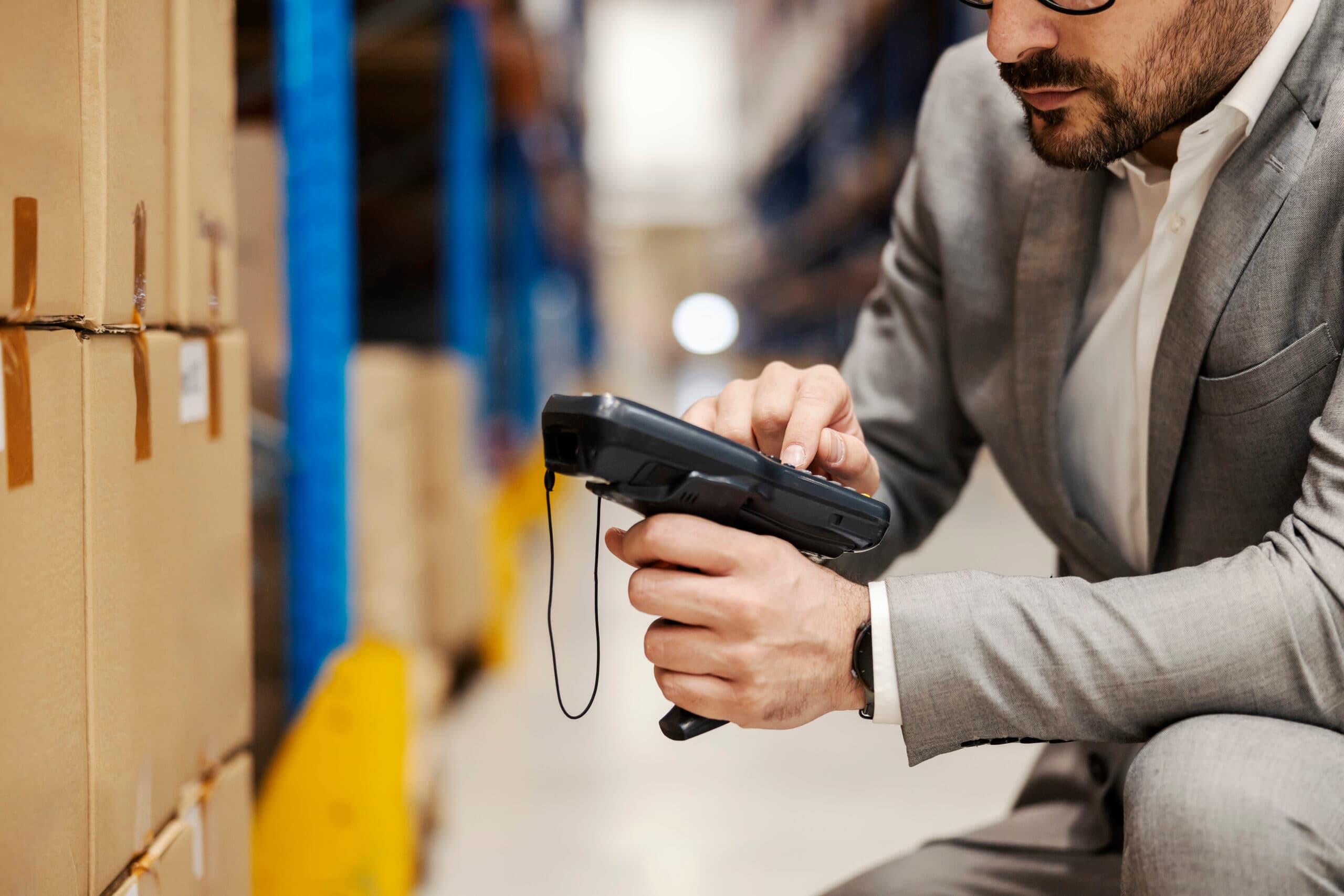 Close-up of a warehouse supervisor using a barcode scanner to manage inventory, highlighting logistics, supply chain management, and efficient warehouse operations.